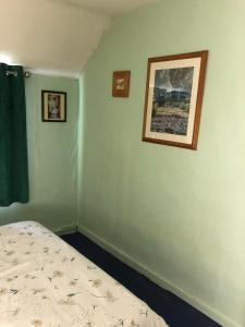 博利厄Double Room in Character Cottage With Parking, Beaulieu, New Forest的卧室配有一张床,墙上挂有两张照片