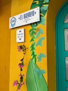 卡塔赫纳El Barrio Hostal的花草花卉黄色墙上的标志
