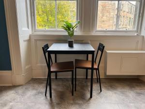 格拉斯哥Cozy Studio Apartment of Glasgows West End的一张桌子,上面有两把椅子和盆栽植物