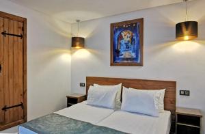 舍夫沙万Aparthotel Dar Nowara Chaouen的卧室配有一张带两盏灯的墙壁床。