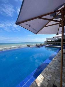 曼塔Hotel poseidon piscina & jacuzzi的一座带遮阳伞的游泳池,位于海边