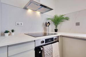 浦耳17 Banstead Road的白色的厨房配有炉灶和水槽