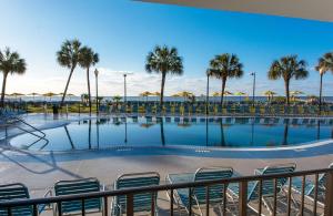 默特尔比奇代顿豪斯度假酒店的一个带椅子和遮阳伞的游泳池以及棕榈树
