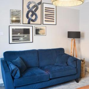 安布尔Avocet Cottage Amble的客厅里一张蓝色的沙发,墙上挂着照片