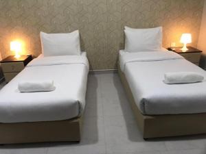 豪尔费坎AL MARSA HOTEL APARTMENTS的配有2张单人床的客房,配有2盏灯
