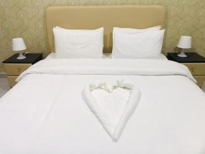 豪尔费坎AL MARSA HOTEL APARTMENTS的一张白色的床,上面有心
