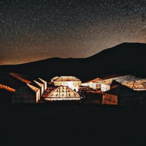 梅尔祖卡Sahara Luxury Glamping的星空之夜,有一群建筑和山脉