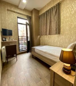 巴库Nizami Street Hotel的一间卧室配有一张床、一张书桌和一个窗户。