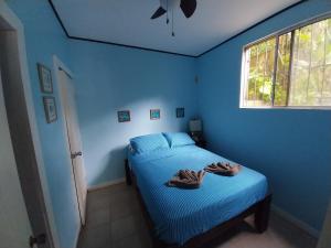 桑迪湾Roatan Backpackers' Hostel的蓝色卧室,配有带毛巾的床