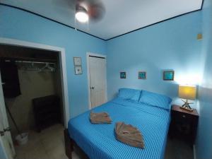 桑迪湾Roatan Backpackers' Hostel的蓝色卧室,配有带2条毛巾的床