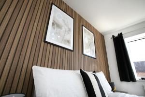 彼得伯勒4 Bed Contractor House-Parking-WiFi-Smart Tvs in Each Bedroom-Special Rates Available的一间卧室配有木制床头板,床上方有两张图片