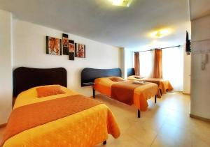 基多HOSTAL MURGEON BOUTIQUE的酒店客房带两张带橙色床单的床