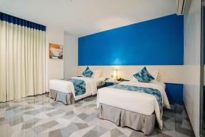 宿务Stacia Hotel powered by Cocotel的酒店客房设有两张床和蓝色的墙壁。