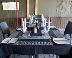 卡蒂马穆利洛Riverside Lodge的一张黑桌,上面放有盘子和酒杯