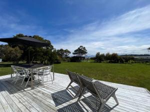 AlonnahBoomers Retreat, Alonnah, Bruny Island的庭院配有桌椅和遮阳伞。