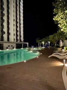 哥打京那巴鲁Cityview Studio Apartment at Kota Kinabalu City Centre的一座游泳池,在晚上在建筑物前
