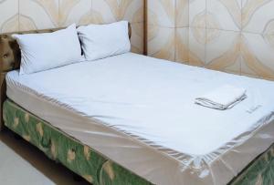 TagumRedDoorz @ PVC Pension Haus的一张带白色床单和枕头的床
