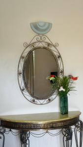 格兰贝伊ibis Apartments - Ground Floor - Summersun Residence - Grand Baie, Pereybere的桌子上带花瓶的镜子