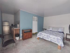 San JoséVilla el paraíso的一间卧室配有一张床铺、一张桌子和一台冰箱