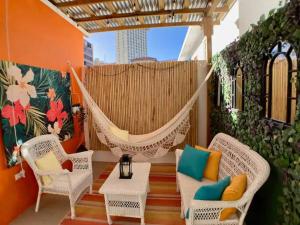 圣胡安Tropical Apartments in Miramar的庭院内的吊床,配有椅子和桌子