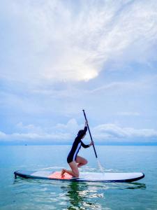 华欣VarietyD-DayHostel HuaHin的一位女士在水面冲浪板上拿着一个桨