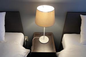 川口市WALLABY HOUSE - Vacation STAY 38651v的一张桌子上的灯,放在两张床之间