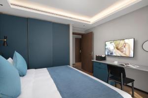 徐州徐州馨乐庭云龙湖公寓酒店的一间酒店客房,配有一张床和一台墙上的电视