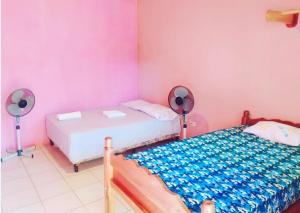 莫约加尔帕Rustic House Hostel的配有粉红色墙壁和风扇的客房内的两张床