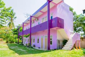 DuriOYO Life 2745 Nabeza House的粉红色和紫色的建筑,有草地庭院