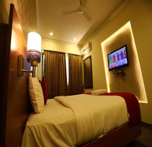NāmakkalDFRONT GOLDEN PALACE的配有一张床和一台平面电视的酒店客房