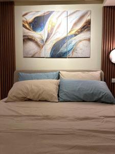 伊洛伊洛Iloilo Travellers Zen Zone的卧室,在床上方墙上装饰有三幅画