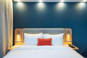 阿斯塔纳Holiday Inn Express - Astana - Turan, an IHG Hotel的蓝色墙壁上一张带红色枕头的床