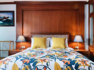 曼谷帕纳莱之家别墅的一间卧室配有一张带木制床头板的床和两盏灯。