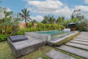 吉安雅Kubu Selat Villa and Glamping的花园内的游泳池配有桌子和遮阳伞