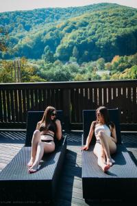 VizhenkaBRB Park Hotel的两个穿着泳衣的女人坐在甲板上的长椅上