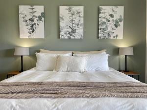 赫罗德斯湾Hilltop 39, Oubaai Golf Estate的卧室配有一张白色床,墙上挂有三幅画作