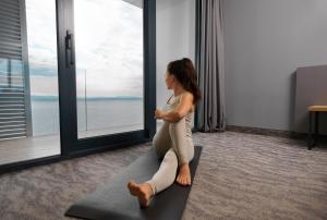 奥帕提亚Hotel Istra - Liburnia的坐在瑜伽垫上的女人,坐在窗户房间里