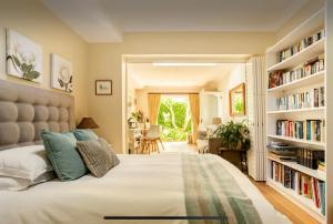 开普敦Guest suite - Leafy Constantia Guest House的一间卧室配有一张带书架的大床