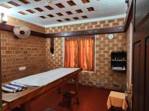 可瓦兰Treebo Trend God'S Own Country Ayurveda Resorts的一间设有桌子和砖墙的房间