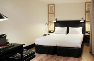 巴塞罗那加泰罗尼亚广场H10精品酒店的酒店客房设有一张大床和一张书桌。