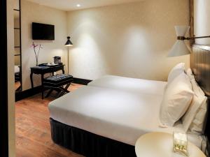 巴塞罗那加泰罗尼亚广场H10精品酒店的酒店客房设有一张大床和一张书桌。