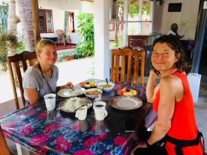 阿鲁甘湾Tropicana Home Stay的两个坐在餐桌边吃着食物的女人
