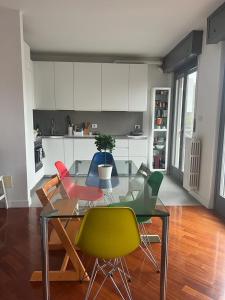 米兰VILLA FENIX MILANO的厨房配有玻璃桌和五颜六色的椅子