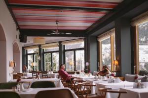 巴德加斯坦豪斯希尔特高山Spa酒店的一间设有桌子的用餐室,有人坐在桌子旁