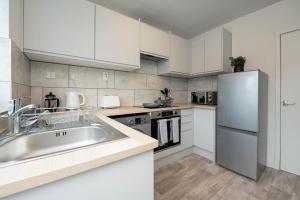 塔姆沃思Watling Apartments Tamworth的厨房配有白色橱柜和不锈钢冰箱