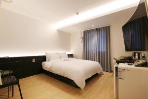 天安市Urban Stay的卧室配有白色的床和电视。