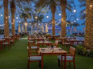 迪拜Life Above Clouds的一间设有桌椅的餐厅,种植了棕榈树