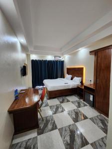 恩德培Pulickal Heights Hotel的配有一张床和一张书桌的酒店客房
