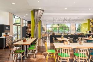 伍珀塔尔Vienna House Easy by Wyndham Wuppertal的餐厅设有木桌和绿色椅子