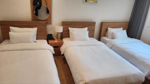 西归浦市Heyy Seogwipo Hotel的配有白色床单和枕头的三张床